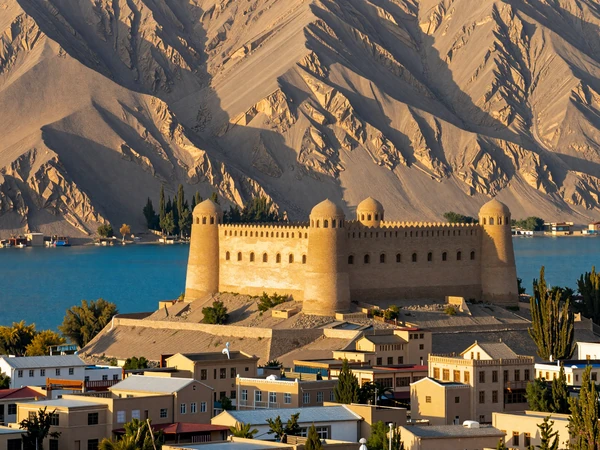 Majestic Pamir mountain landscape in Tajikistan with traditional village and turquoise alpine lake, showcasing the breathtaking beauty of the Roof of the World